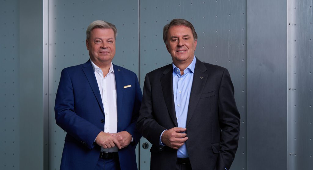 Harald Servus links im blauen Anzug rechts davon Wolfgang Ecker im dunklem Anzug vor einer Stahltür in grau