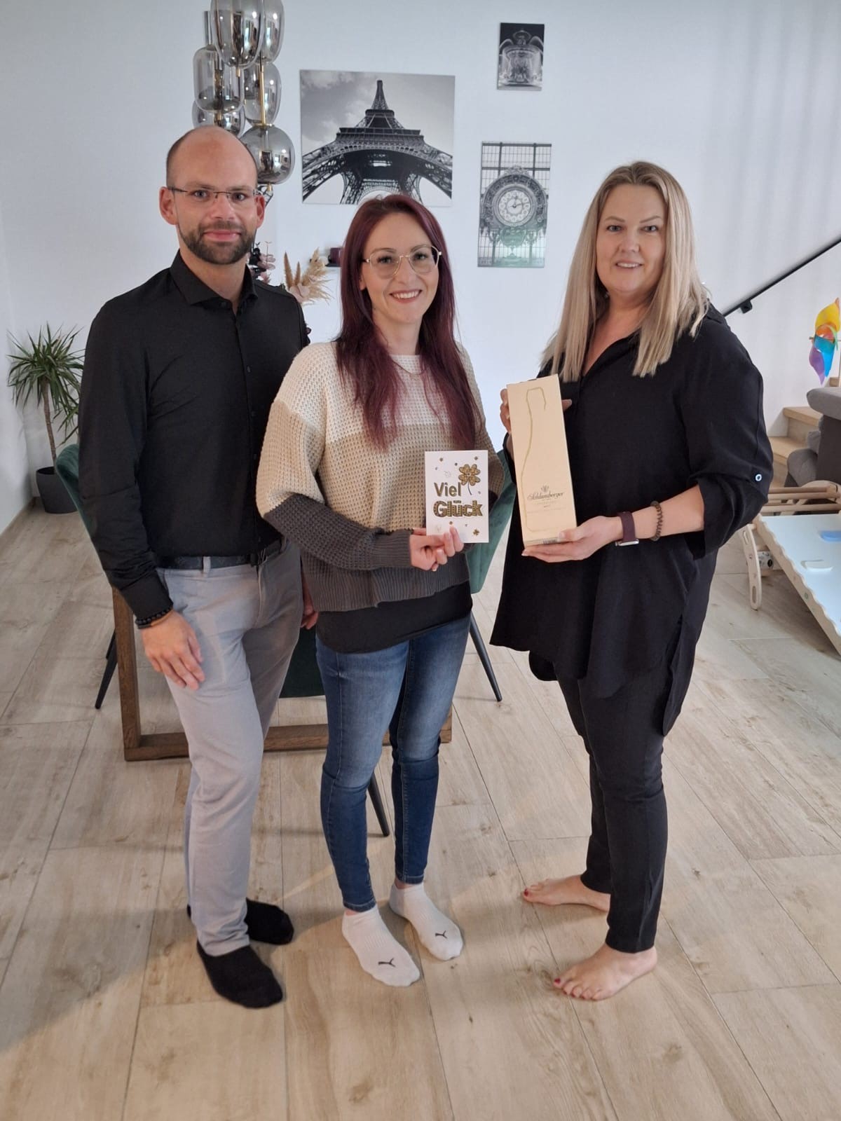 Glückwünsche zur Eröffnung von HairMotion in Baden: Drei Personen bei der Geschenkübergabe mit „Viel Glück“-Karte und Schlumberger Sektpräsent.