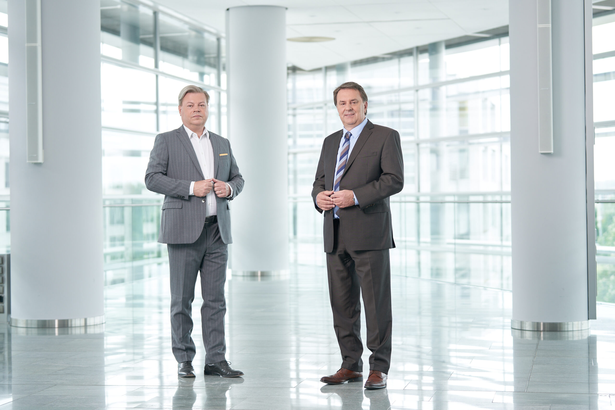 Harald Servus im grauen Anzug links vor einer Glasfront, rechts neben ihm im dunklem Anzug Wolfgang Ecker