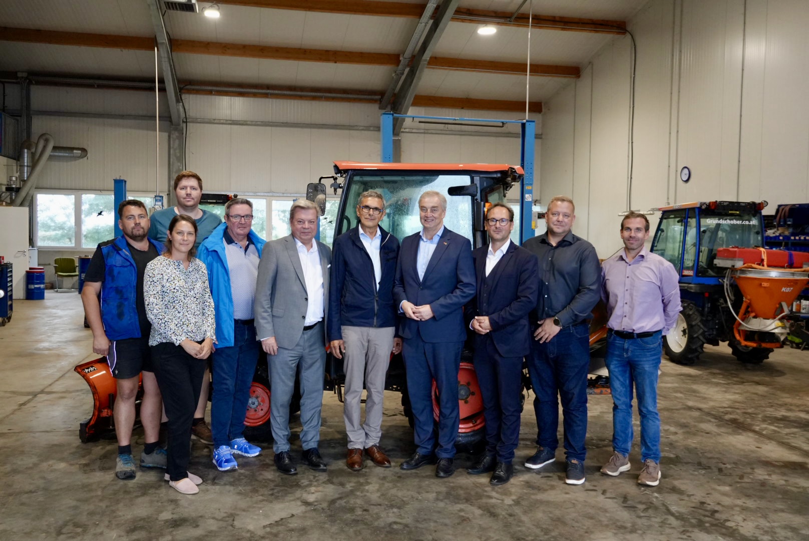 Auf dem Bild befinden sich die Vertreter des Unternehmens sowie die des Wirtschaftsbundes vor einem Traktor in einer Halle