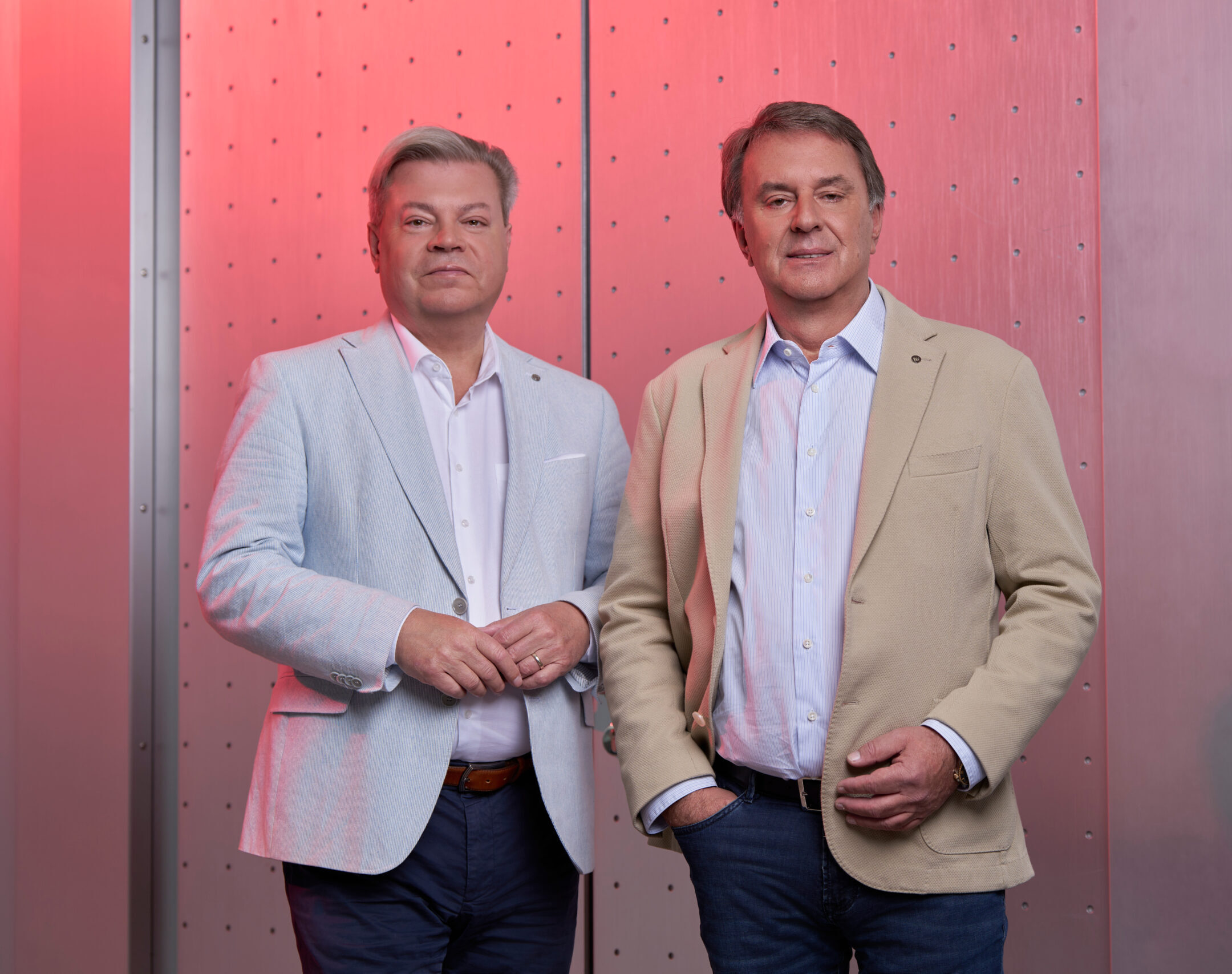 Harald Servus links im hellem Anzug und Wolfgang Ecker im hellem Anzug vor rotem Hintergrund