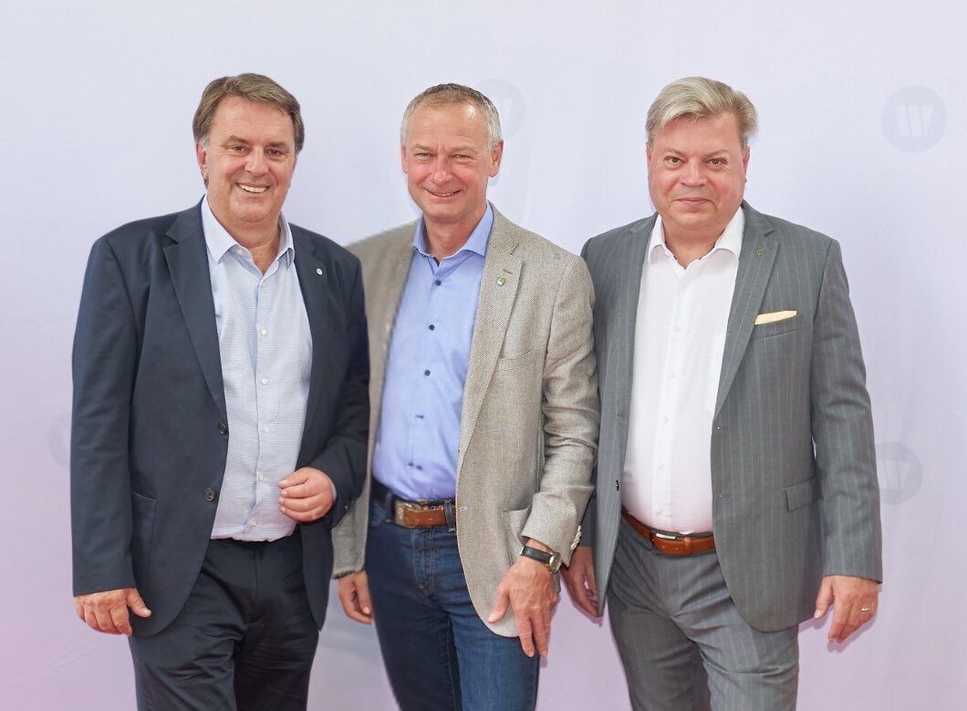 Links Wolfgang Ecker im dunklem Anzug in der Mitte Manfred Denk im hellem Blazer und daneben links Harald Servus im grauen Blazer. Sie stehen vor einem weißem WB Roll Up